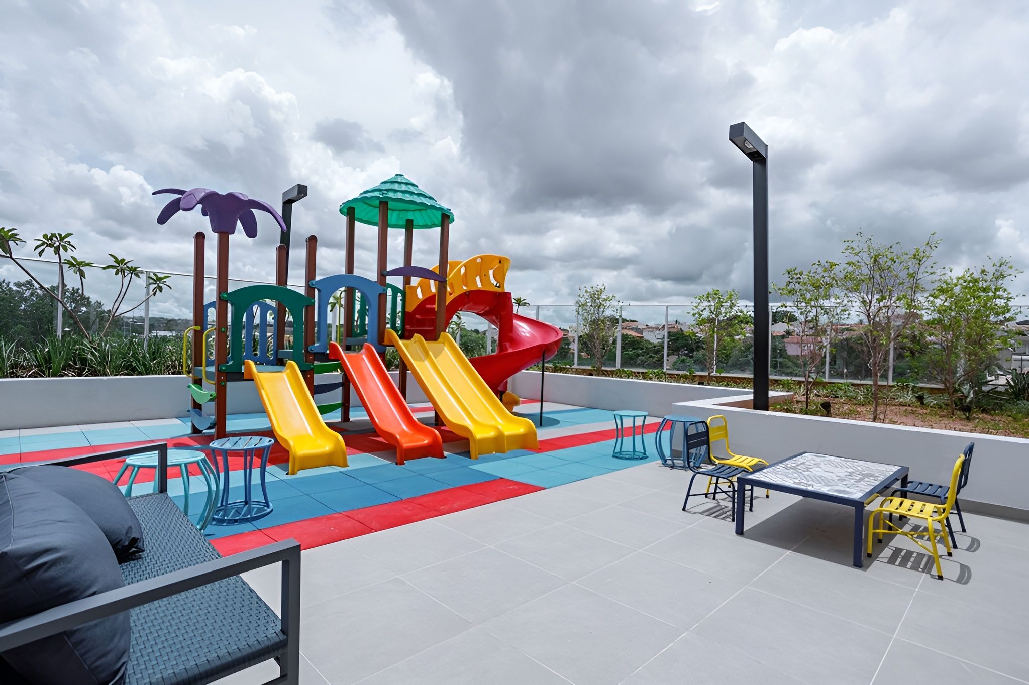 An outdoor play area with slides and climbing structures, surrounded by seating and a table.