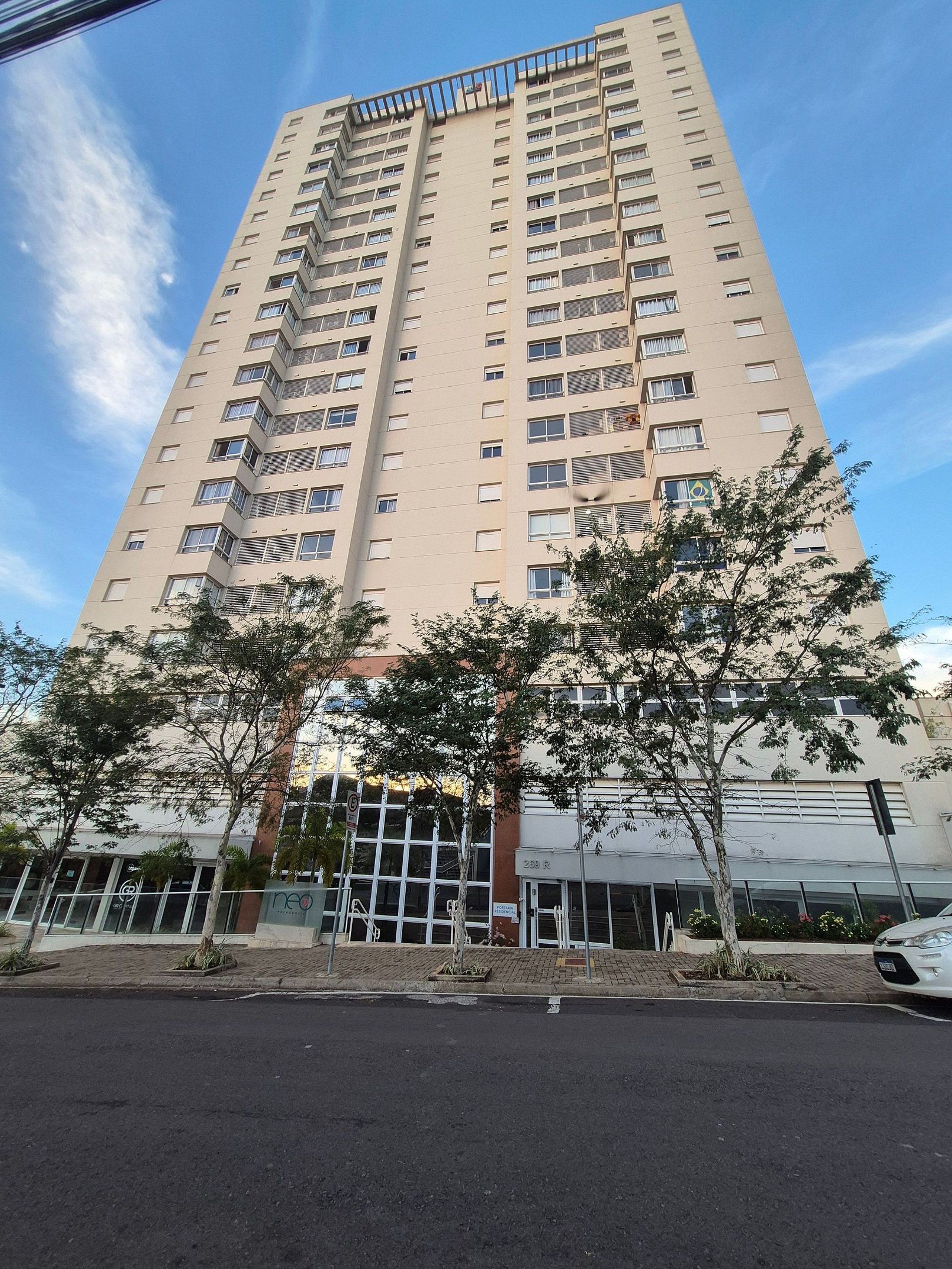A high-rise building with multiple floors, balconies, and a clear sky.