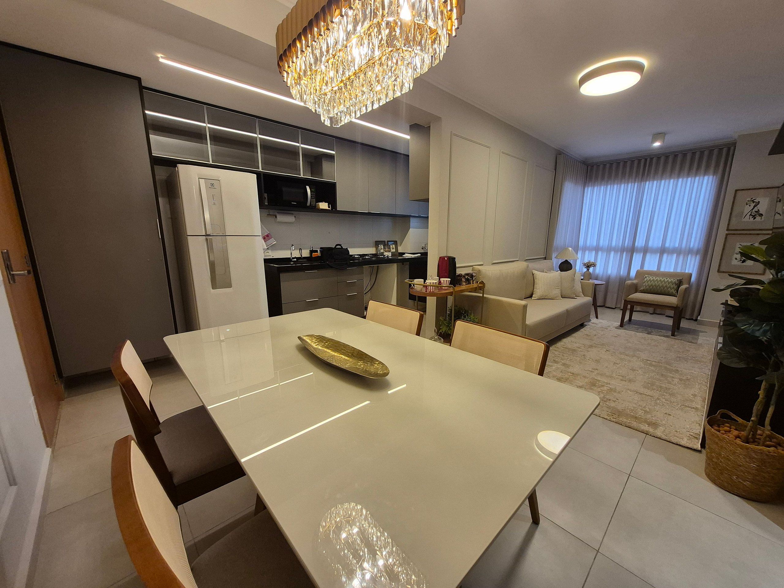 Une cuisine moderne avec un coin repas, un lustre et un salon comprenant un canapé et des fauteuils.