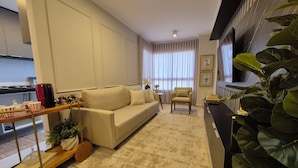Ein modernes Wohnzimmer mit einer Couch, einem kleinen Tisch und einer Pflanze.