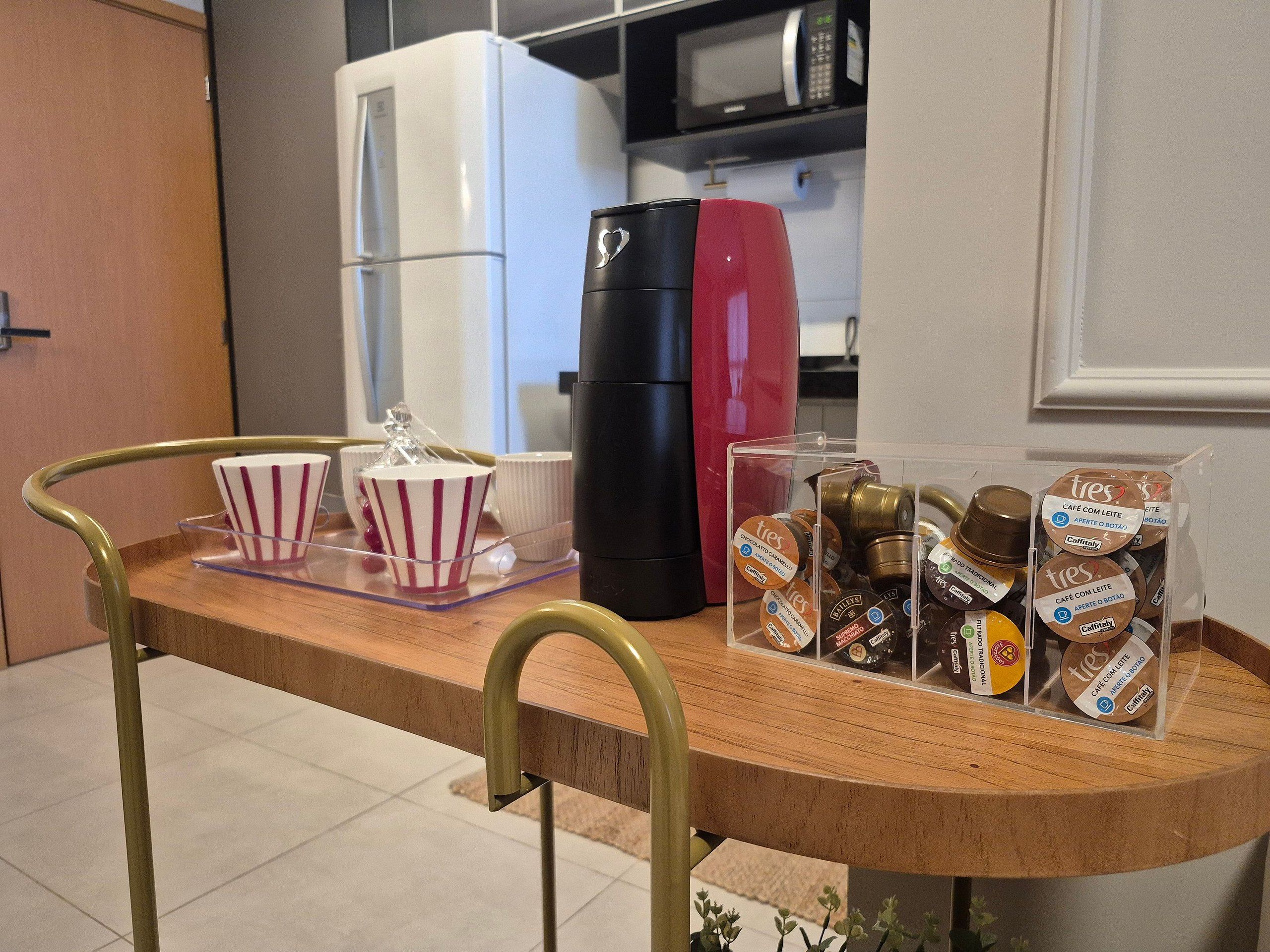 A kitchen counter with a coffee machine, a refrigerator, and a display of coffee pods.