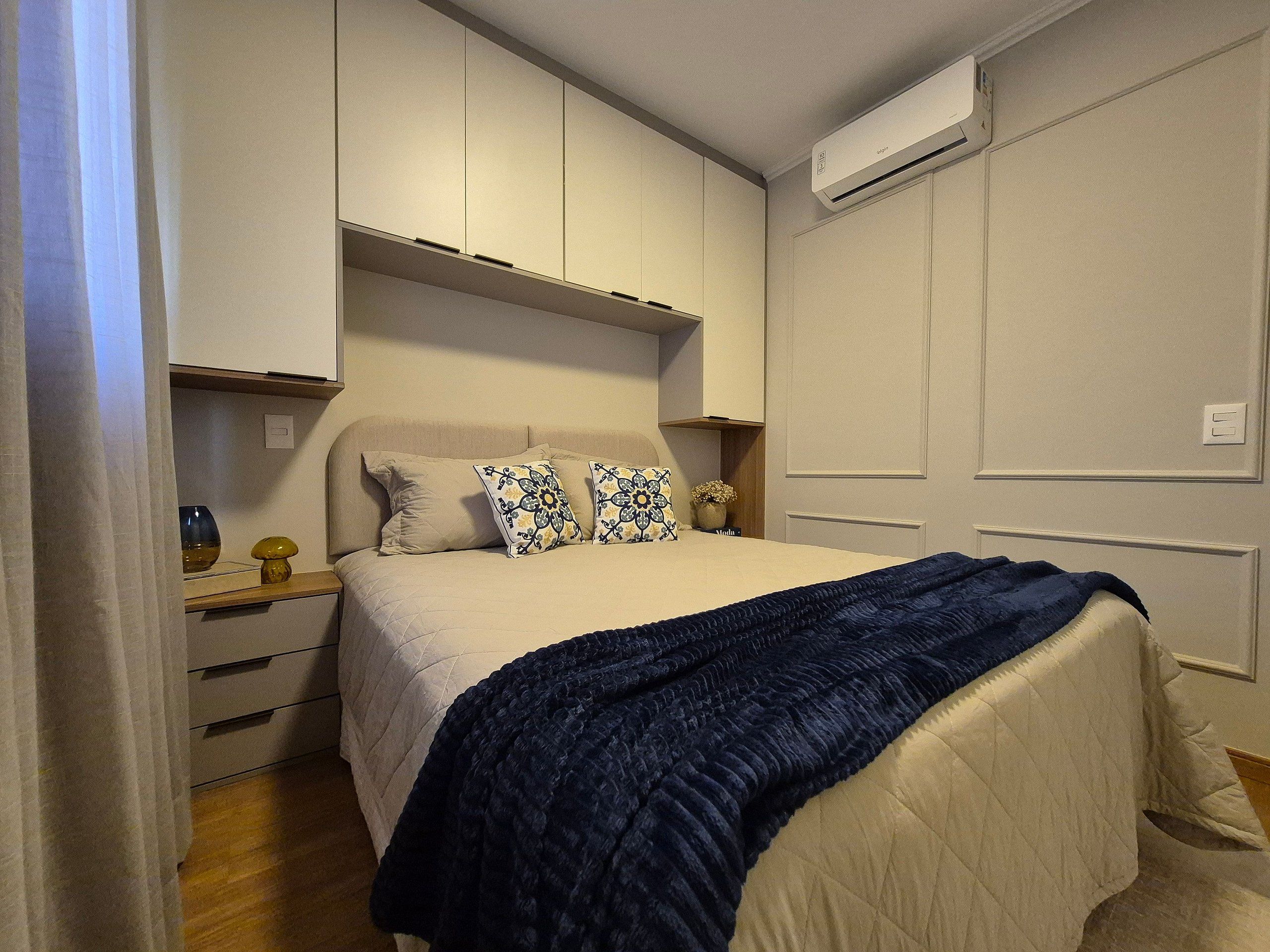 A bedroom with a bed, bedside tables, a wardrobe, and an air conditioning unit.