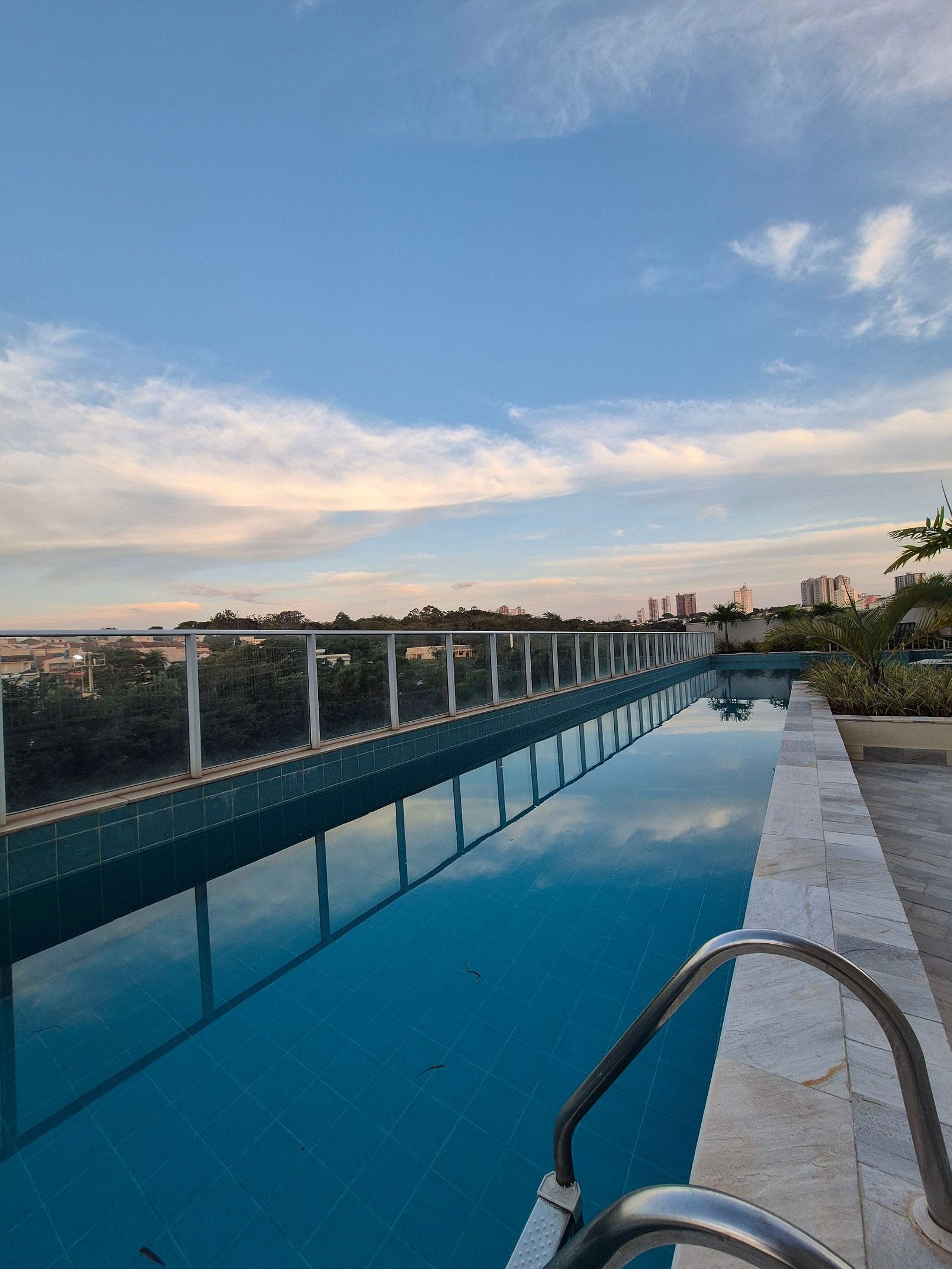 A swimming pool with a clear view of the surrounding landscape and distant buildings.