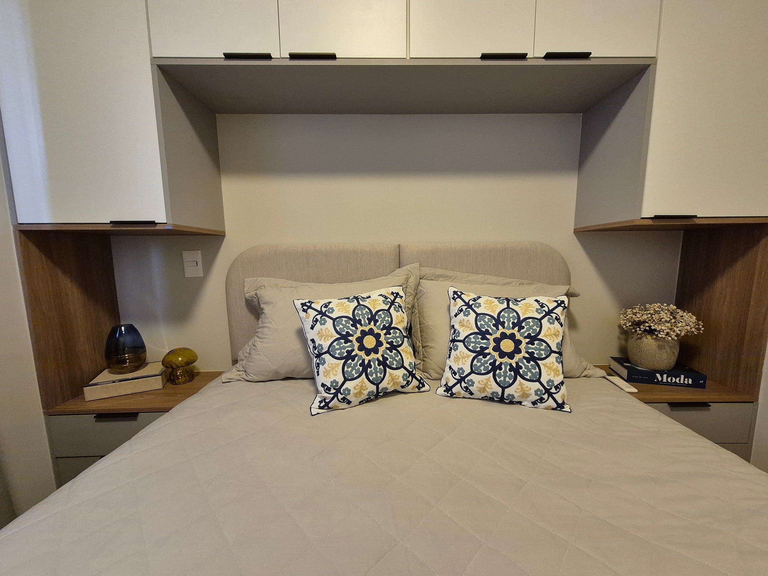 Ein Schlafzimmer mit einem Bett, zwei Kissen, einem Nachttisch mit einer Vase und einem Buch mit dem Titel 'Moda'.