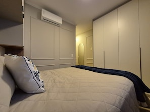 A bedroom with a bed, a pillow, an air conditioning unit, and a wardrobe. - PP - Neo Petrópolis - Apto NP148 (Presidente Prudente)