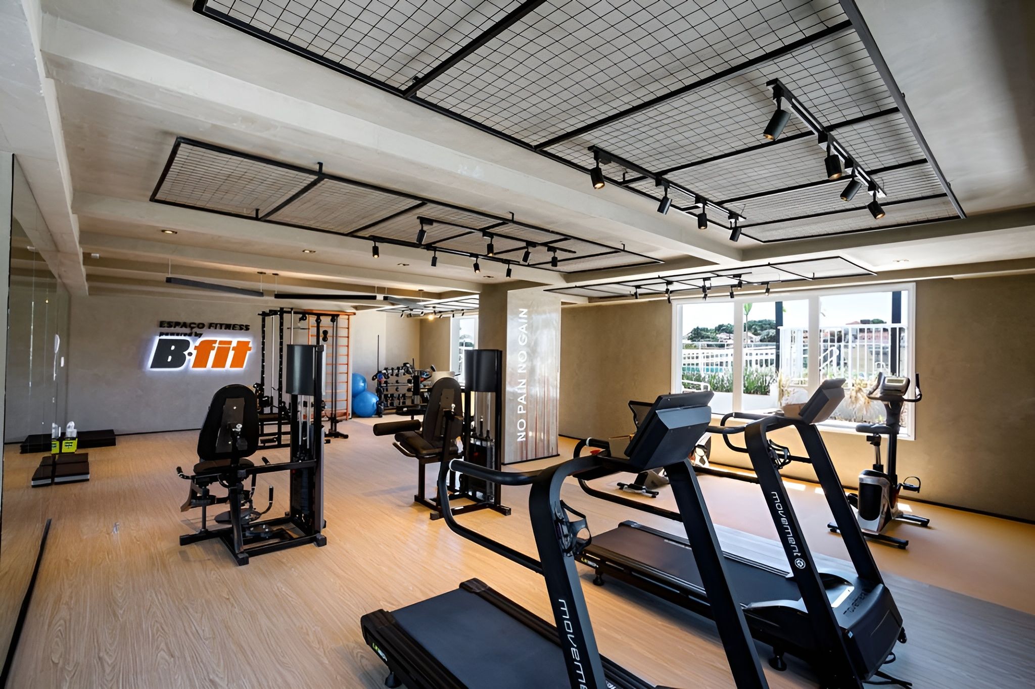 A gym with cardio equipment, weight machines, and a wall with a logo.