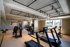 A gym with cardio equipment, weight machines, and a wall with a logo. - PP - Neo Petrópolis - Apto NP148 (Presidente Prudente)