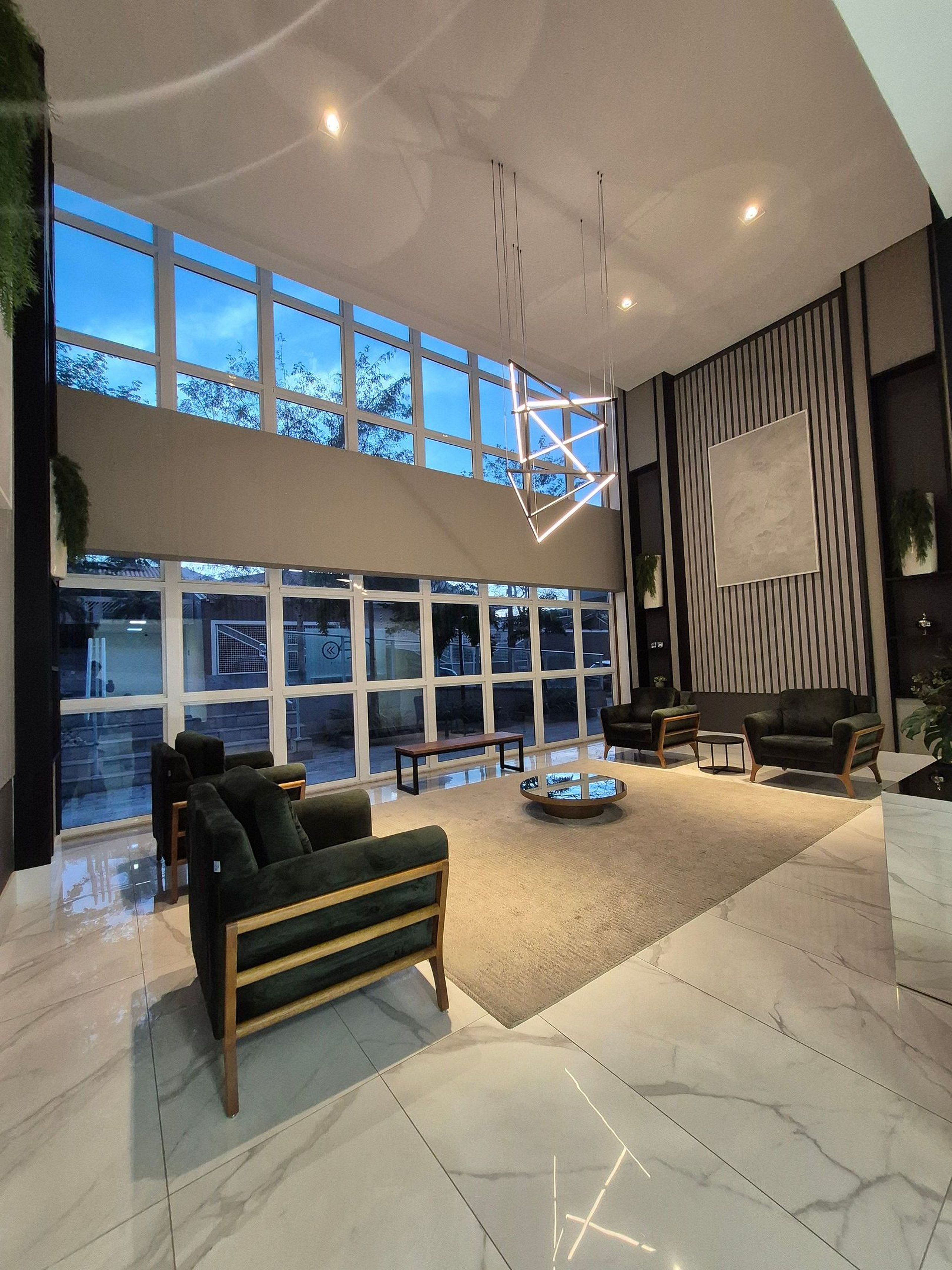 A spacious lobby with a high ceiling, large windows, and modern furniture.