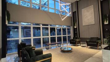 A spacious lobby with a high ceiling, large windows, and modern furniture.