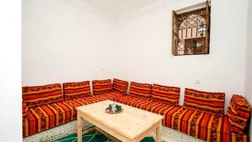 A room with a wooden table and a sofa set with patterned cushions.