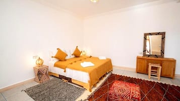 A bedroom with a bed, a nightstand, a dresser, a mirror, and a patterned rug.
