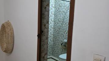A narrow hallway with a mirror reflecting a bathroom with a toilet and a shower.