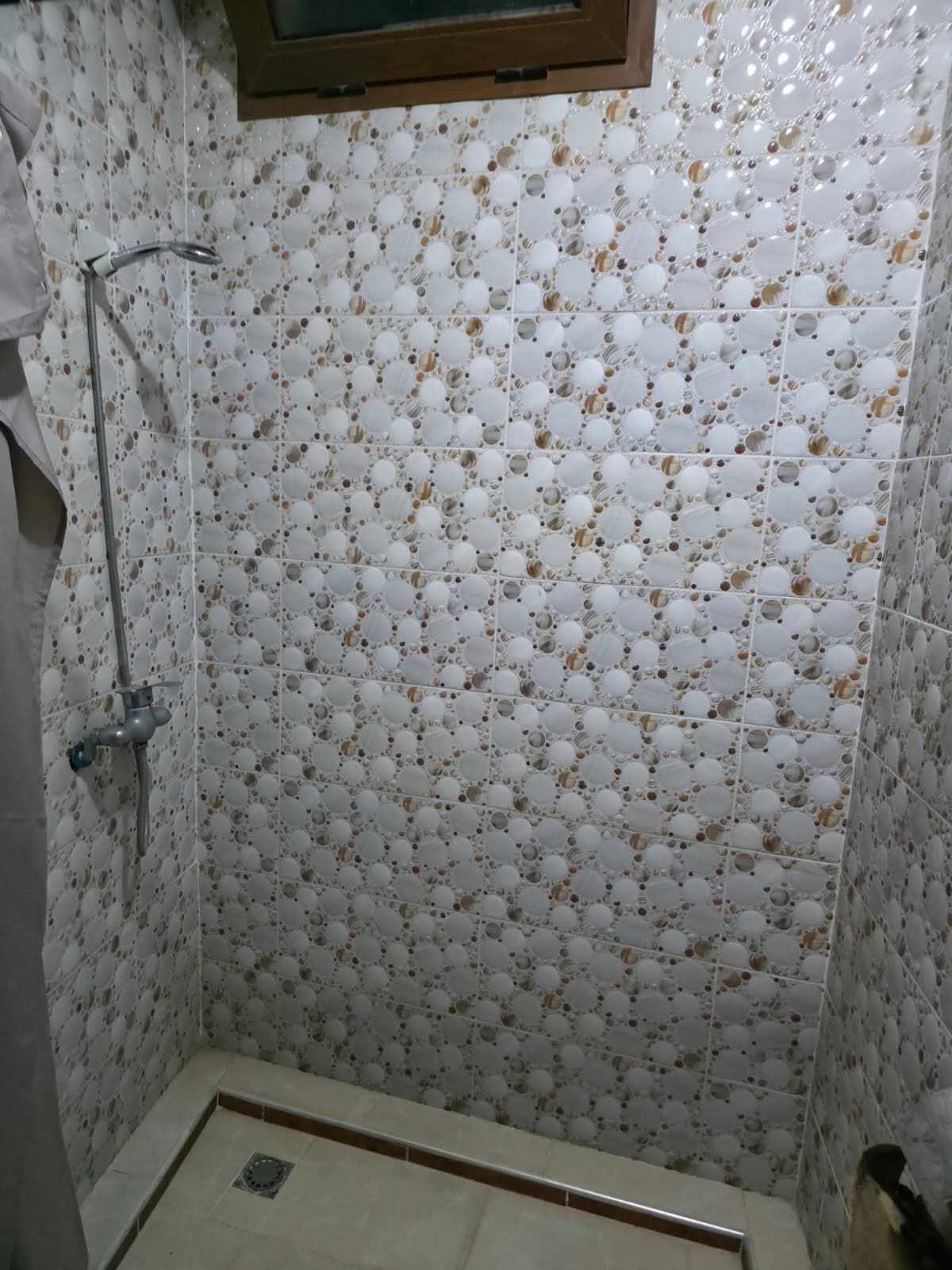 Ein Badezimmer mit Dusche, gefliesten Wänden und einem Fenster.