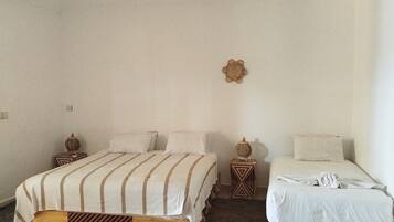 A bedroom with two beds, a woven ceiling light fixture, and a patterned rug.
