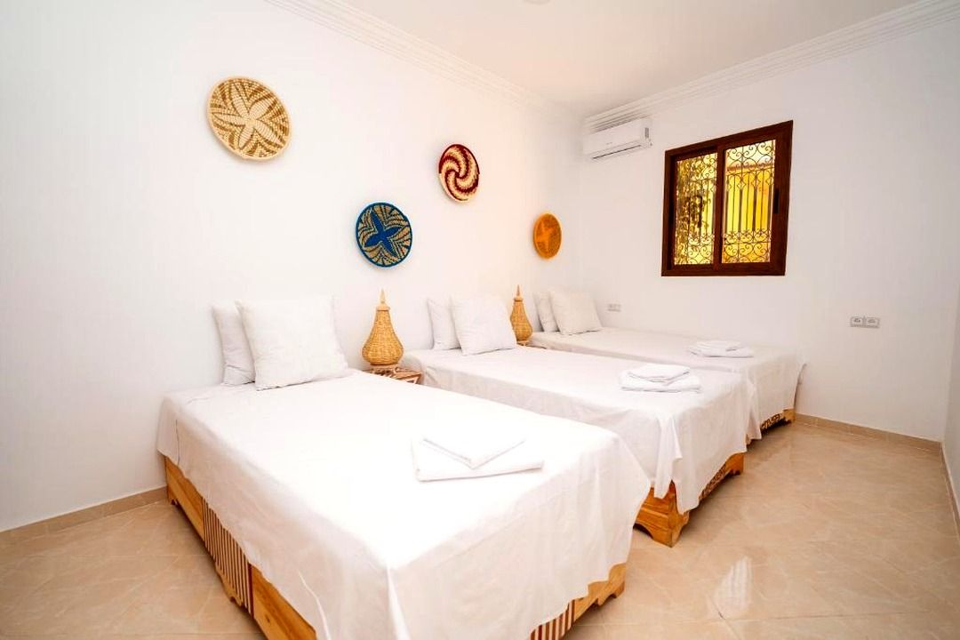 Une chambre d’hôtel avec deux lits, une fenêtre ornée d’une grille décorative et des œuvres d’art murales.