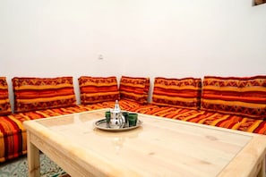 Um quarto com uma mesa de madeira, um sofá e uma bandeja com bule e xícaras.
