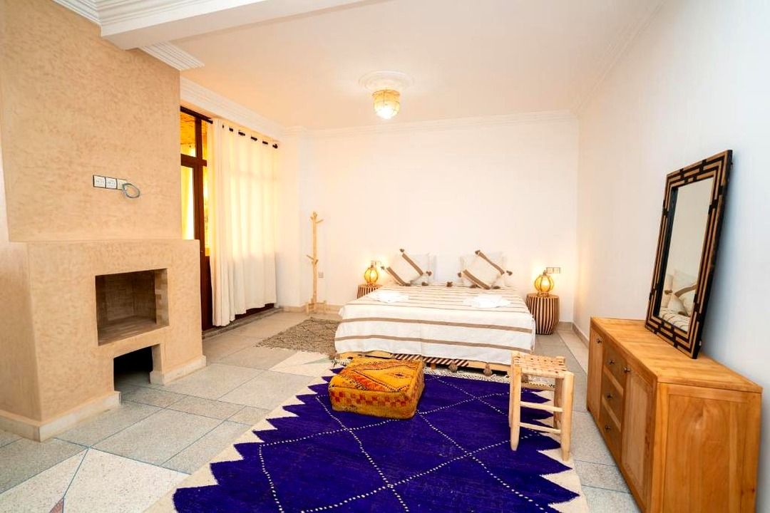 A bedroom with a bed, bedside lamps, a wooden cabinet, and a mirror on the wall.
