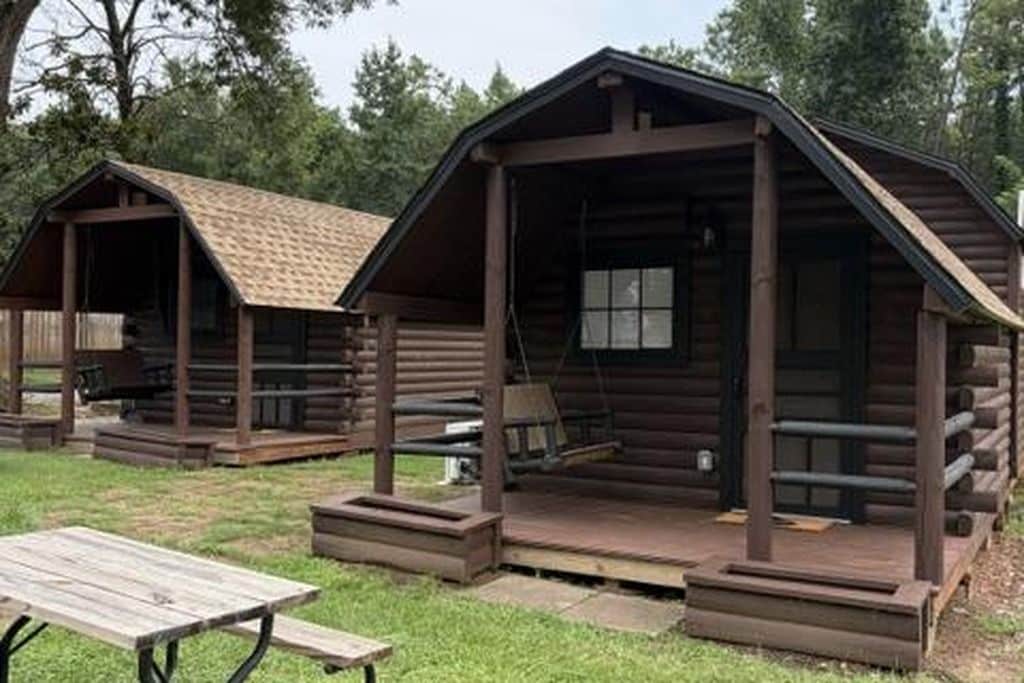 Un chalet rustique doté d’une véranda, d’une table de pique-nique et d’un petit espace de détente extérieur.
