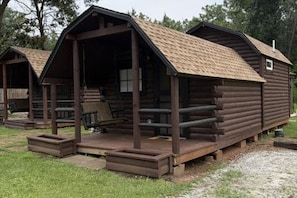 A row of log cabins with a porch and a small window. - Atlanta South Cabin Getaway, a Cozy Stay Near I-75 (McDonough)