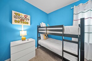 A bunk bed with white bedding, a nightstand with a lamp, and a wall sign. - 4BR house with private pool in Solara Resort (Kissimmee)