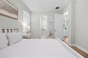 Une chambre à coucher avec un grand lit, une table de chevet avec une lampe et un tableau accroché au mur.