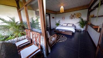 A room with a bed, a seating area with chairs, and a view of the outdoors.