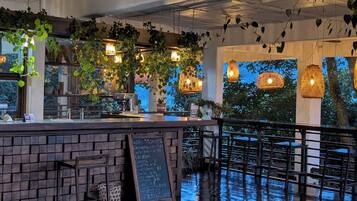 A bar area with a chalkboard menu, hanging plants, and pendant lighting.