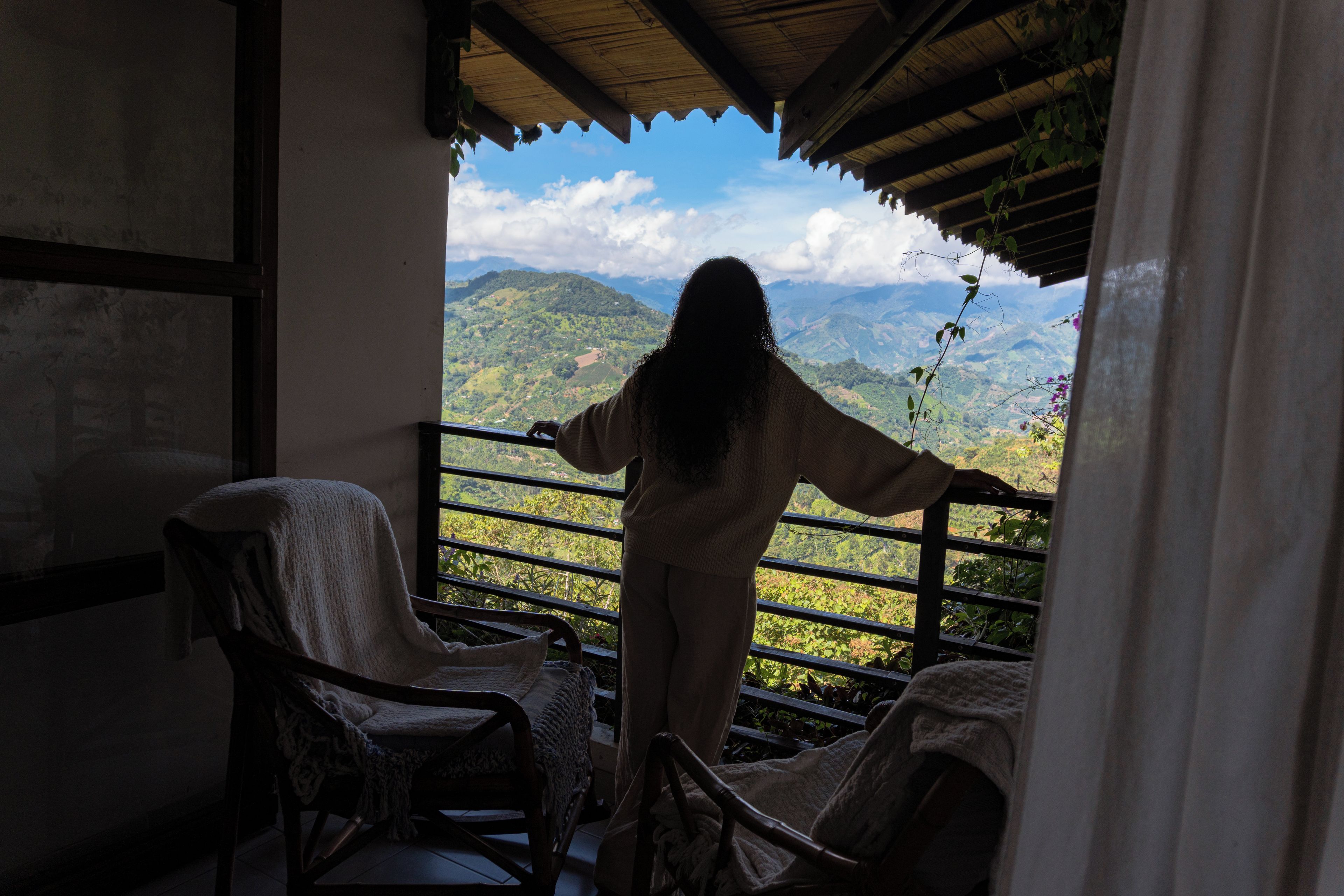 Una persona de pie junto a un balcón con vistas a un paisaje montañoso.