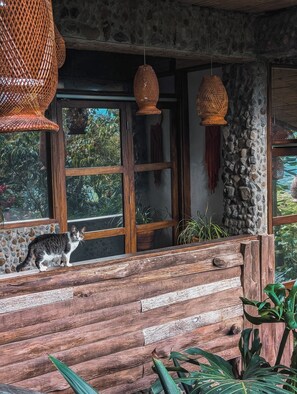 Un interior rústico con un gato sobre un banco de madera, paredes de piedra y lámparas colgantes de tejido.