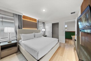 Ein modernes Hotelzimmer mit einem großen Bett, Nachttischlampen, einem Flachbildfernseher und einem begehbaren Kleiderschrank.