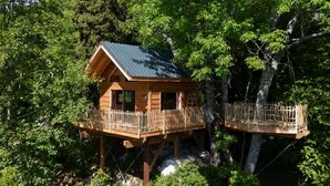 Una cabaña de madera con balcón, rodeada de árboles.