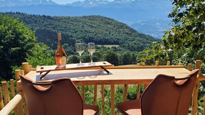 Un espacio de comedor al aire libre con una mesa y sillas, con vistas a un paisaje montañoso.
