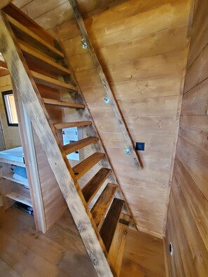 A wooden staircase with a metal handrail and a window at the top.