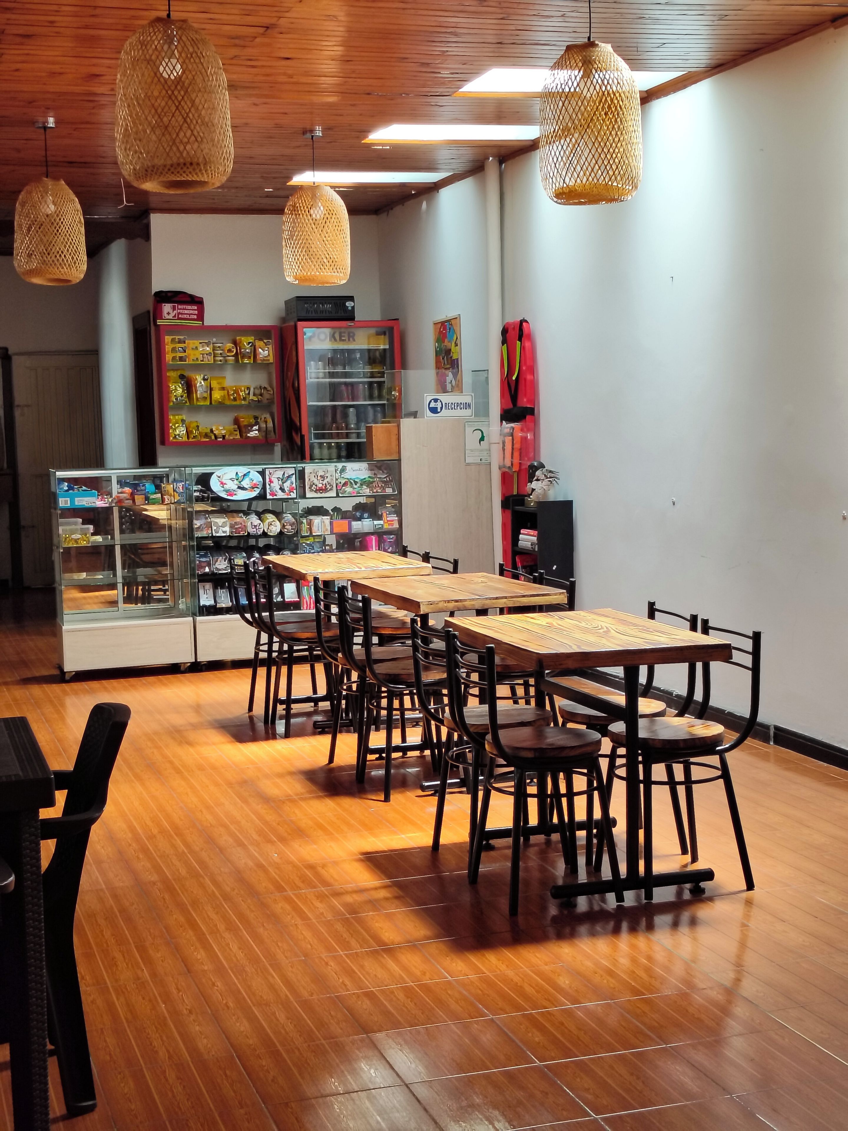 A restaurant with wooden tables and chairs, hanging wicker lamps, and a reception area.