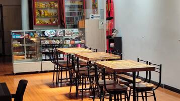 A restaurant with wooden tables and chairs, hanging wicker lamps, and a reception area.
