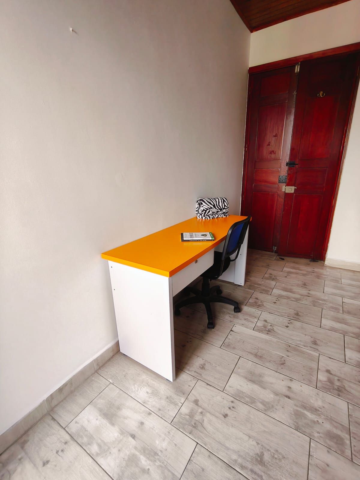 Een kamer met een bureau, stoel en een rode deur.