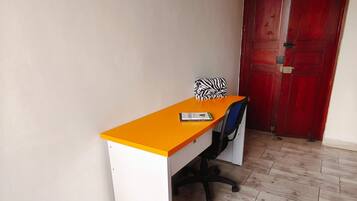 Een kamer met een bureau, stoel en een rode deur.