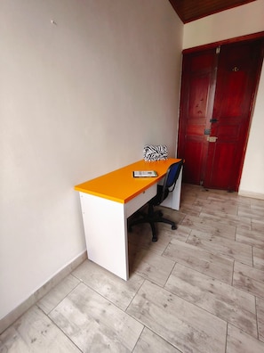 A room with a desk, chair, and a red door.