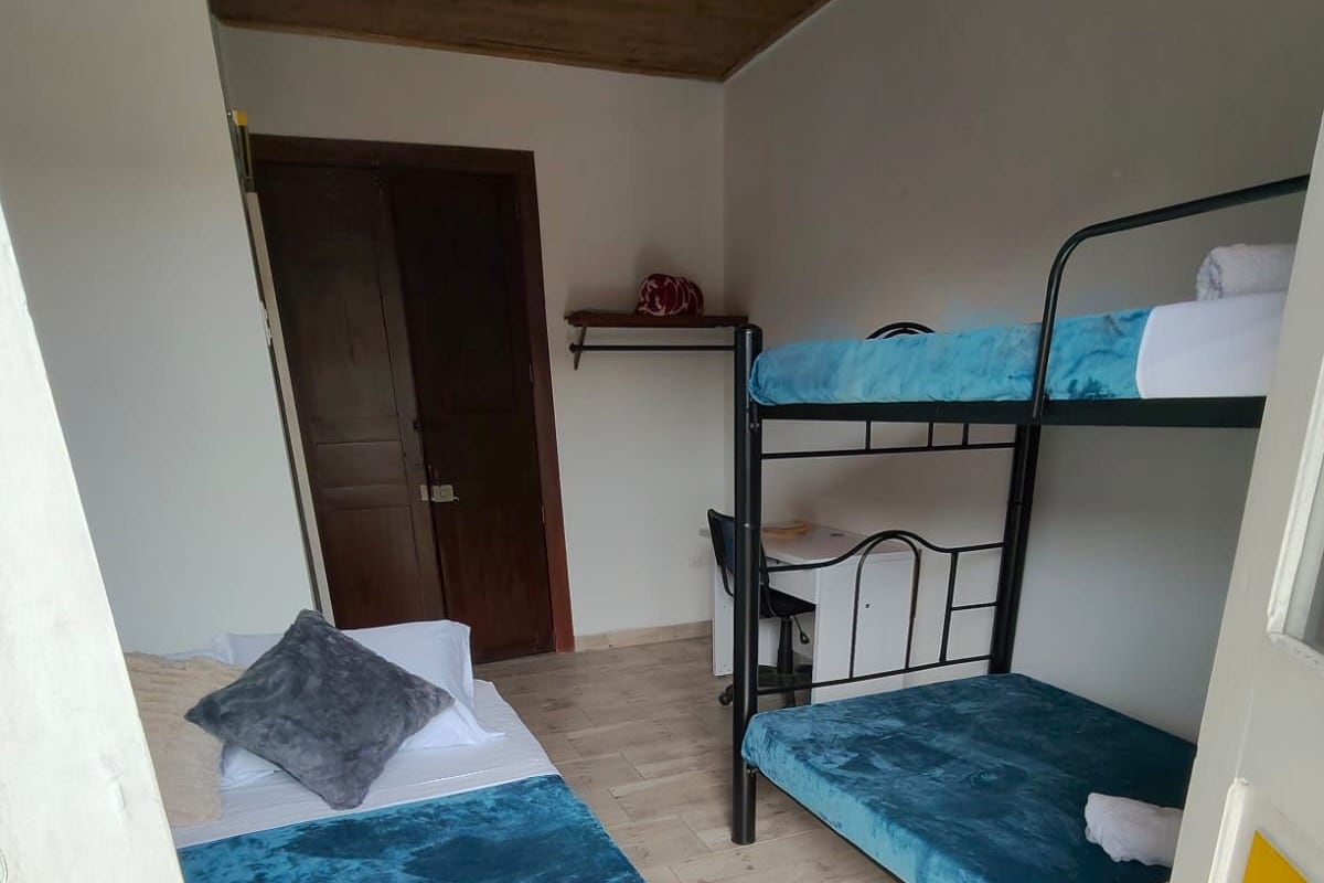 A room with two bunk beds, a desk, and a door.
