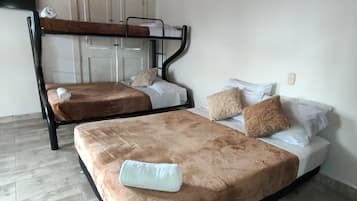 Een kamer met twee bedden, een houten plafond, een witte deur en een televisie.