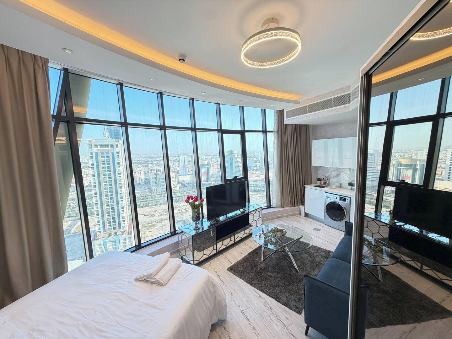 Ein modernes Hotelzimmer mit einem großen Bett, einem Fernseher, einer Sitzecke und Blick auf die Stadt.