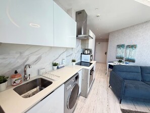 Eine moderne Küche mit integriertem Waschtrockner, ein Essbereich mit einer Couch und ein Wohnzimmer mit einem Bild an der Wand.