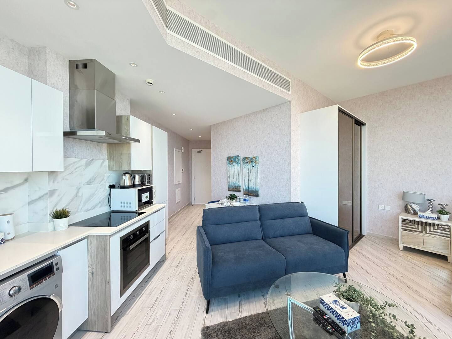 Una cucina moderna con elettrodomestici integrati, una zona pranzo con divano e un soggiorno con tavolino in vetro.