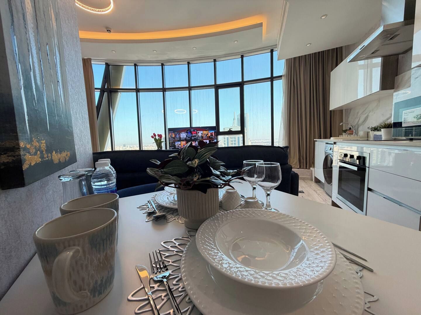A modern kitchen with a dining area, large windows, and a view of the city.