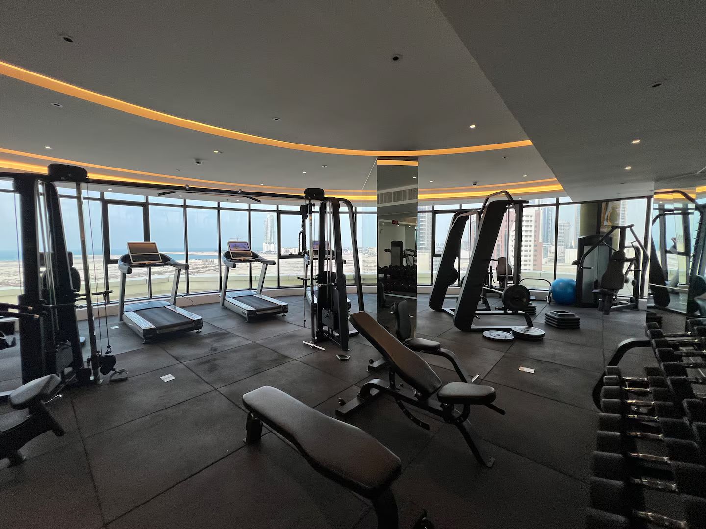 A gym with treadmills, weight machines, and a bench.