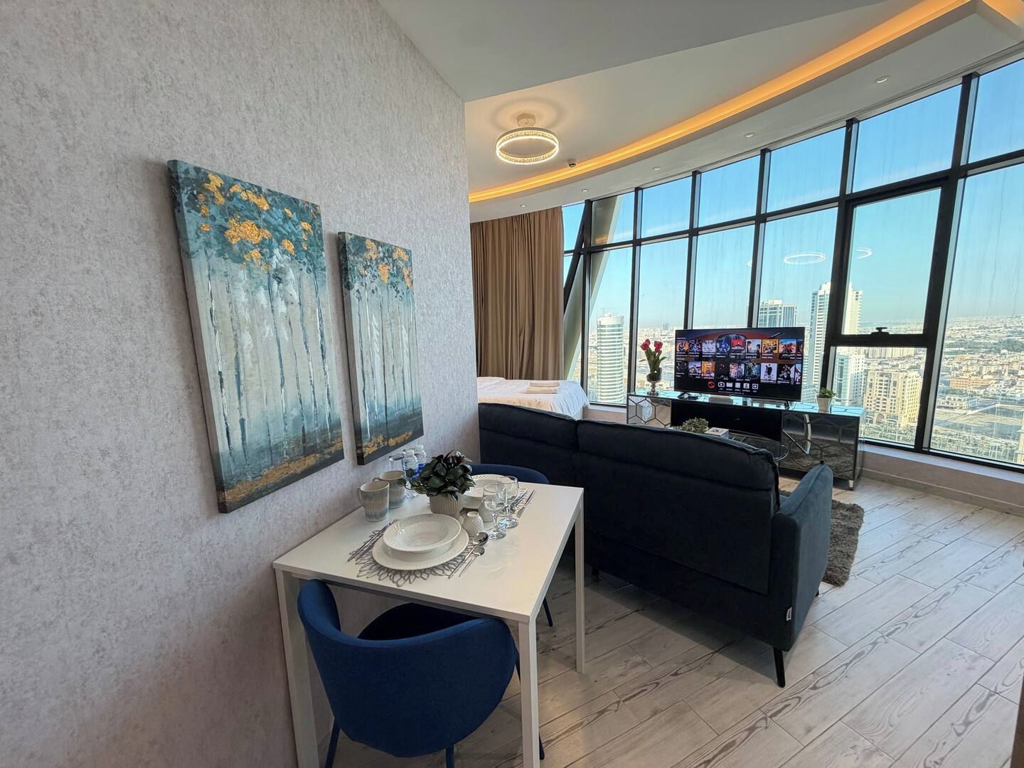 Una sala de estar moderna con comedor, ventanas amplias y obras de arte en las paredes.