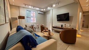 Uma sala de estar moderna com sofá, mesa de centro e televisão na parede.