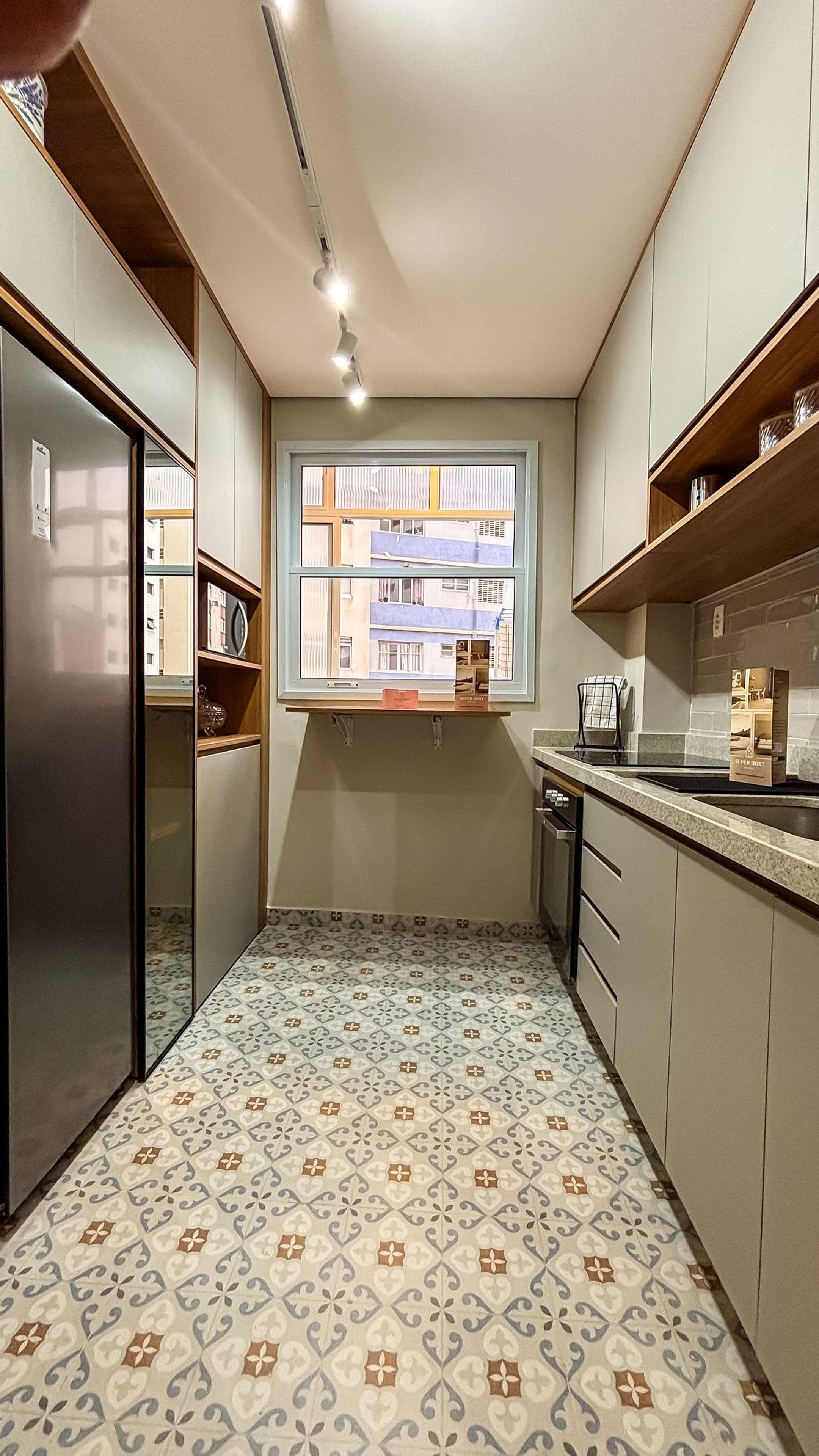 A compact kitchen with a window, built-in appliances, and patterned flooring.