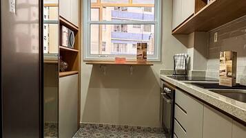 A compact kitchen with a window, built-in appliances, and patterned flooring.