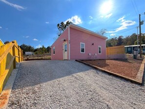 A pink building with a gravel driveway and a wooden fence. - Pink House in Holiday Island (Eureka Springs)